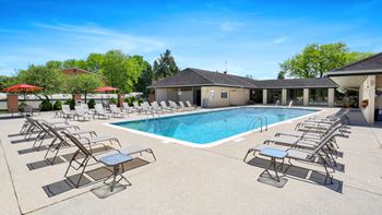 A pool with sun loungers and a building in the background at The Waverly on the Lake - Belleville, MI Apartment , Belleville, Michigan